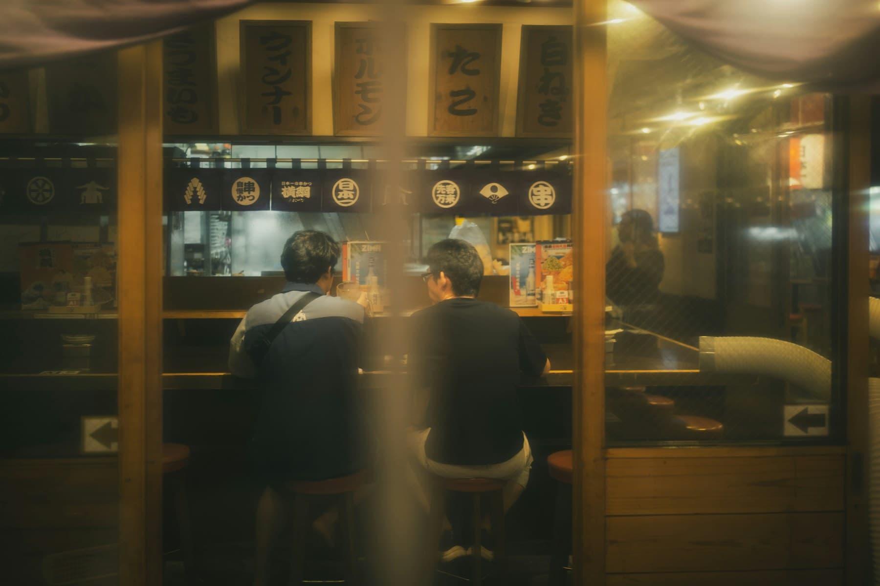 飲食店のカウンターで過ごす二人の客
